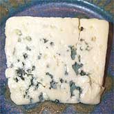 Deep pockets of blue mold on a ripe piece of Roquefort cheese